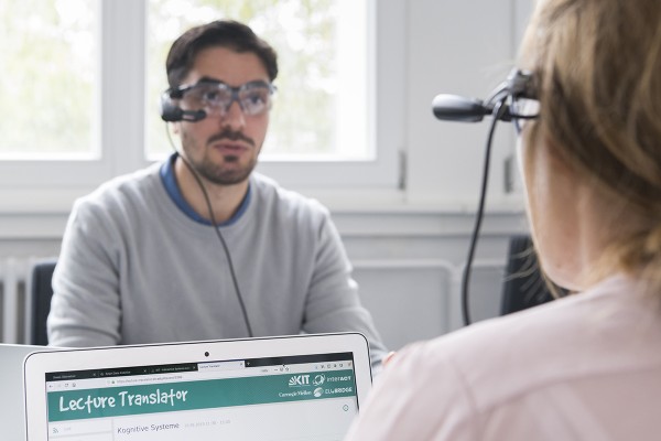 Two adults looking at each other with small computers strapped to glasses on their faces