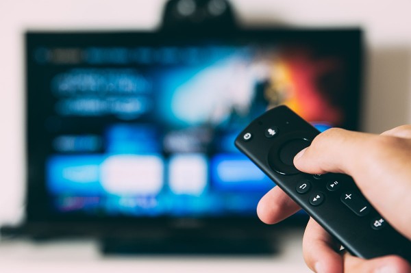 Hand holding a remote in front of a TV